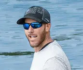 Ein Mann mit Kappe und Sonnenbrille lacht