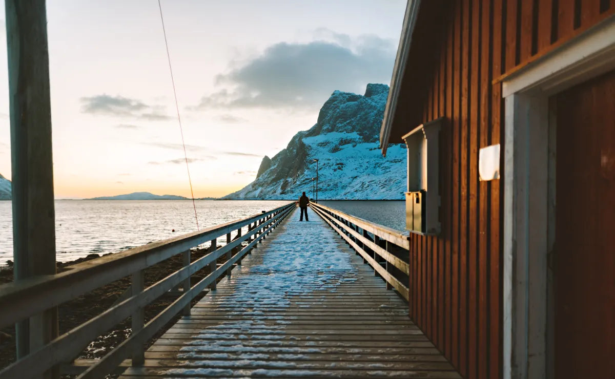 Angeln in Norwegen: das Foto zeigt einen Mann auf einem Steg einer norwegischen Hütte am Meer. 